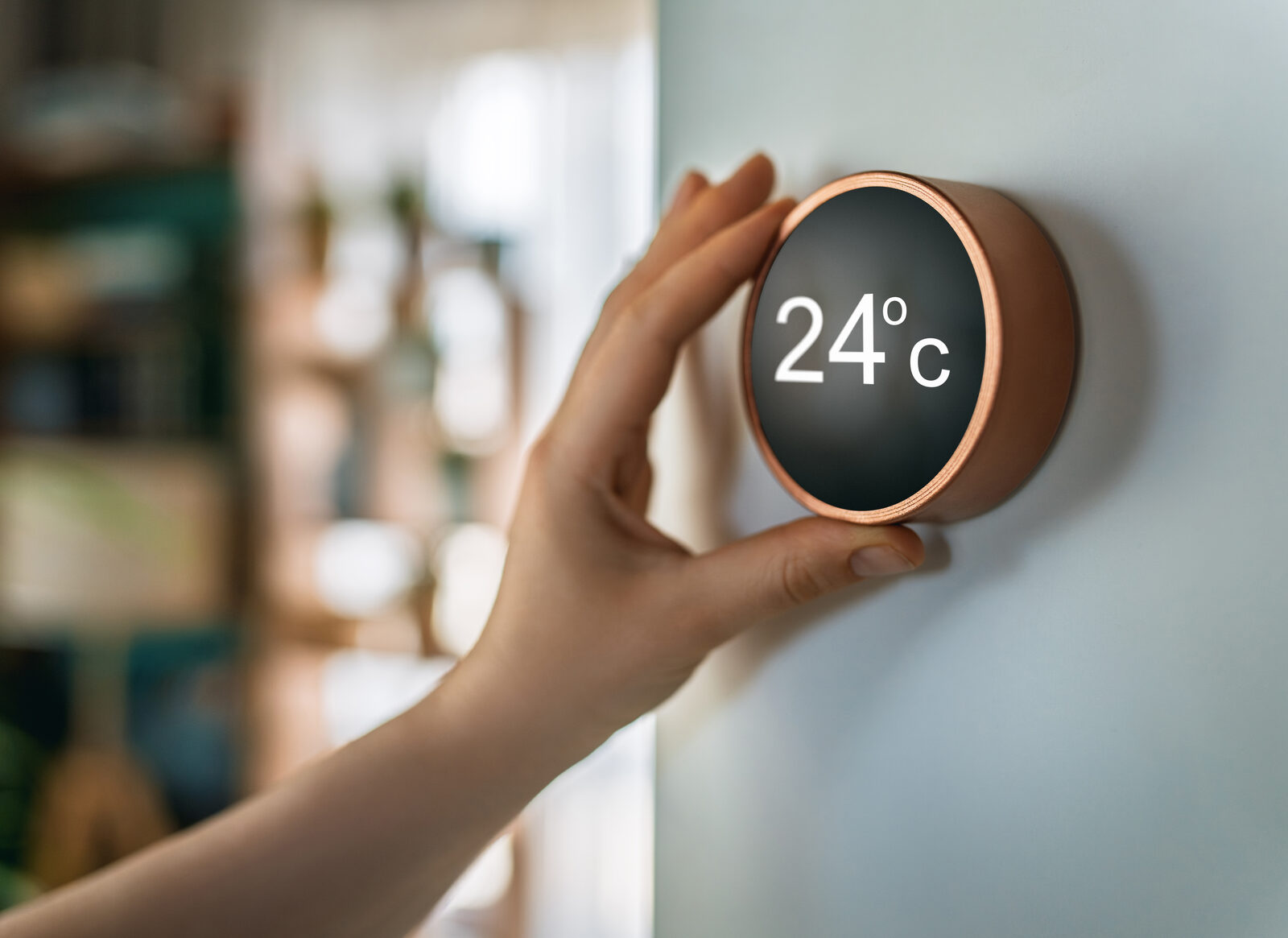 Hand adjusting a modern circular smart thermostat mounted on a wall