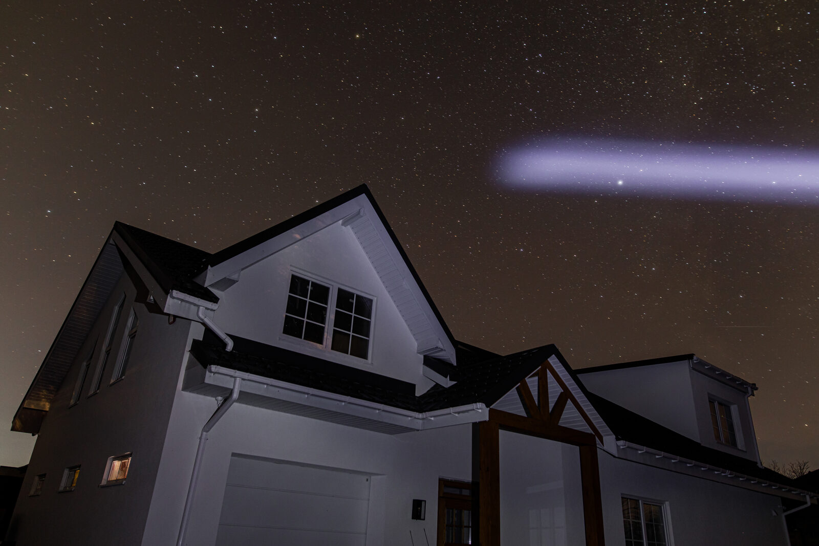 Two-storey suburban house at night under a star-filled sky