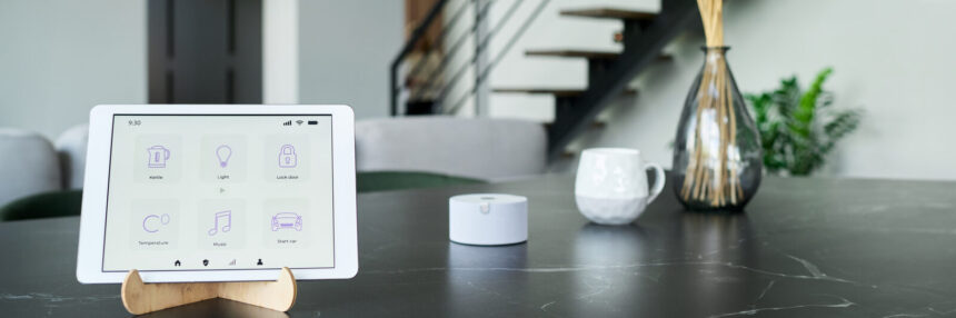 Tablet showing a smart home control panel beside a small white hub on a table