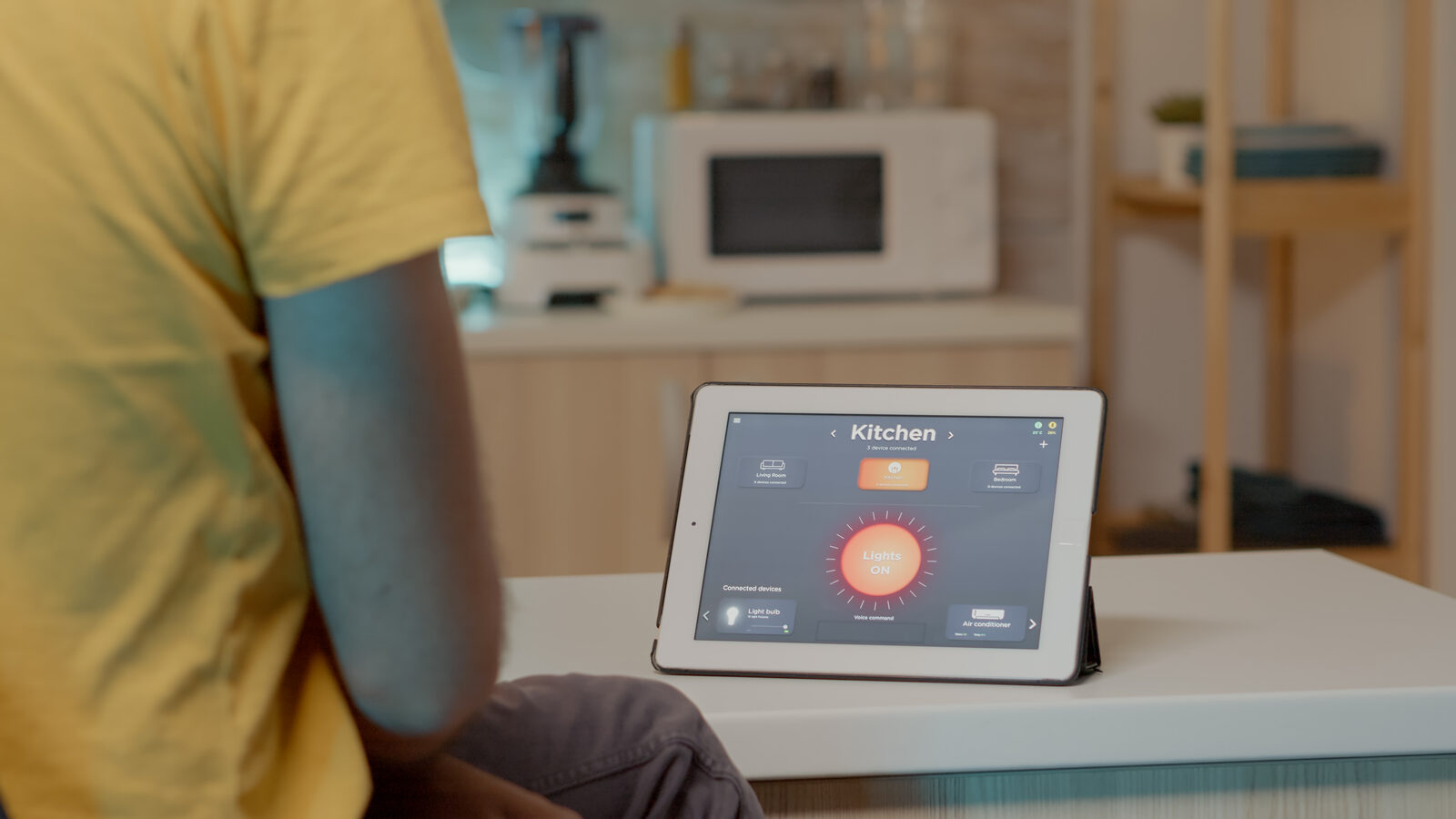 Person using a tablet showing a home automation dashboard in a kitchen
