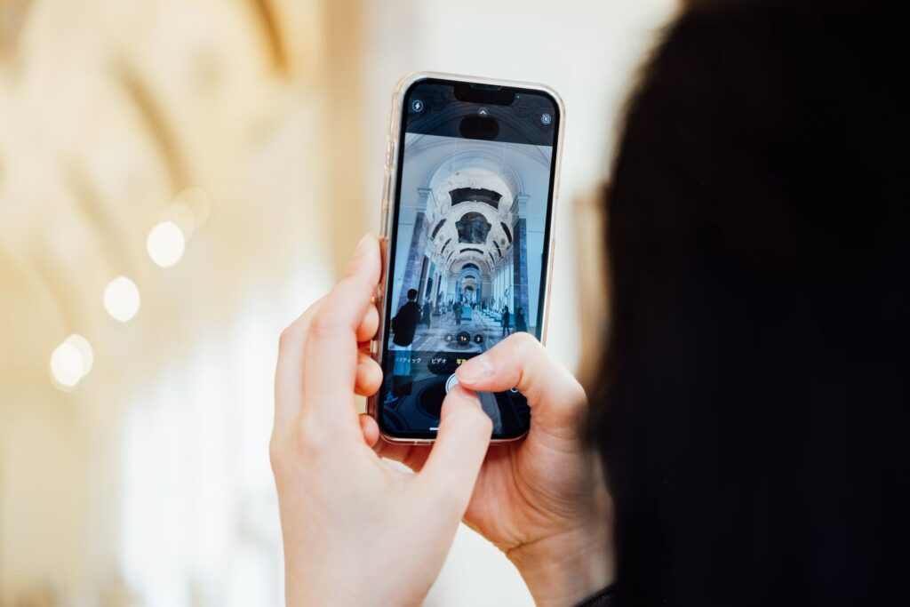 Person framing an architectural corridor on an iPhone, illustrating smartphone camera settings for composition.