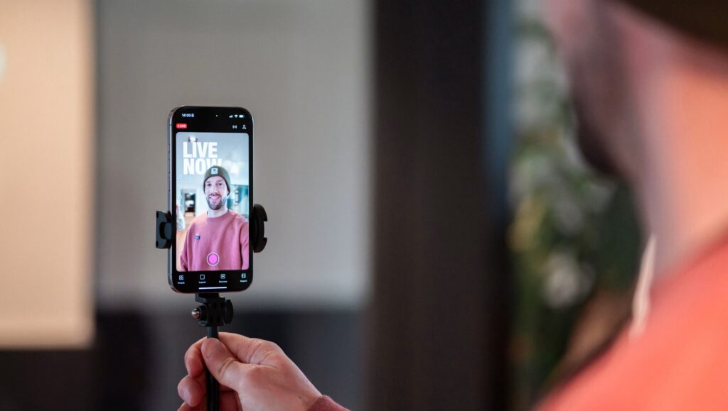 Creator filming with an iPhone on a handheld grip, illustrating smartphone camera settings for video.